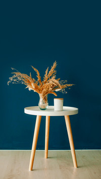 Vase with dry grass on the table on a blue background