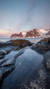 View over rocks and rockpools to snowy Oksen mountains