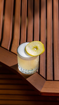 Cocktail with ice, apple and froth in a glass on the table