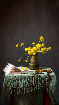 Yellow dandelions in a vase and an open book on the table