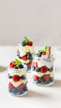 Raspberry and blueberry parfait with cheese cream in jars