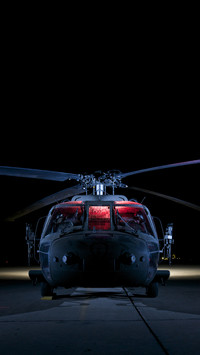 A uh60 black hawk helicopter lit up by multiple external