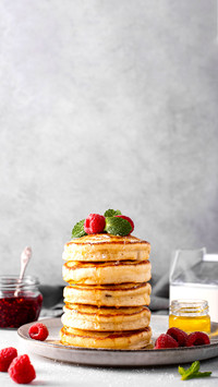 A stack of lush pancakes with raspberries and honey
