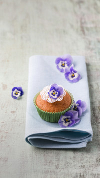 Muffin with horned violets on napkin