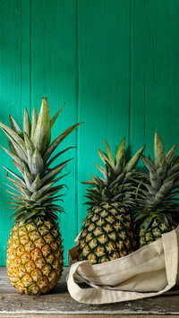 Fresh tropical pineapple standing next to more pineapples