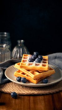 Honey blueberry waffles in front of dark background
