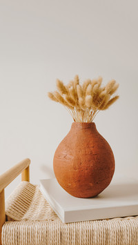 Bunny tail grass bouquet in clay pot on rattan bench