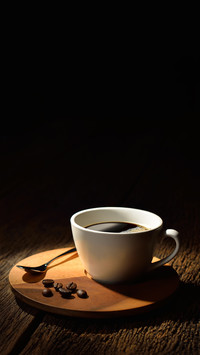 Cup of coffee and coffee beans on old wooden background