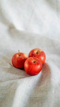 Three red apples on grey linen cloth