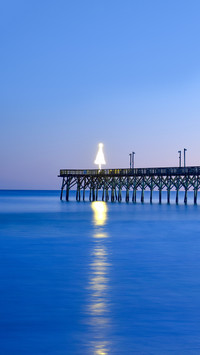 The photo of a fishing pier extending out into the ocean