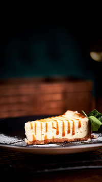 Piece of Cheesecake on black plate on a table with mint