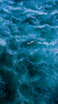 Surfer paddling through lightning waves