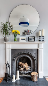 Round mirror above open fireplace with classic surround