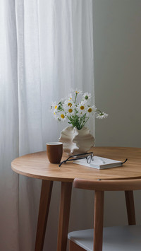 A glass of coffee on a round wooden table in the living room