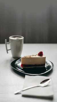 Piece of raspberry cheesecake dessert on a black plate