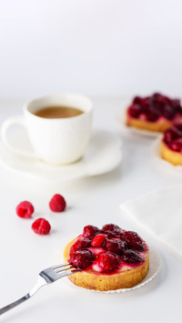 Tartlets with raspberries on white background