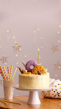 Delicious cake decorated with sweets and burning candle