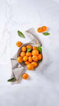Sweet tangerines in a ceramic bowl with linen napkin