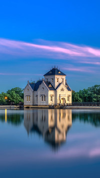 A serene view of a building reflected in a calm lake