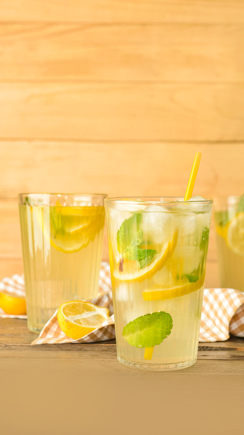 Glasses of tasty cold lemonade on wooden background preview