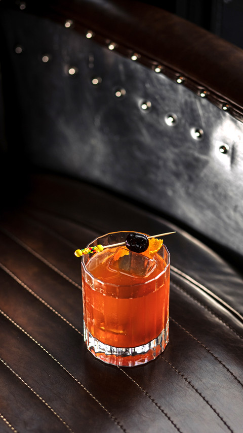 A cocktail with ice and a toothpick with olives in a glass preview