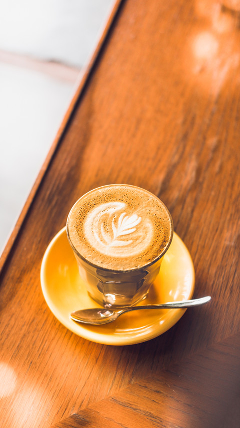 The coffee on yellow plate placed on the wooden table preview