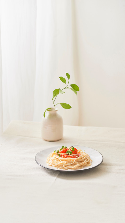Paghetti bolognese sauce in white dish and a vase of plants preview