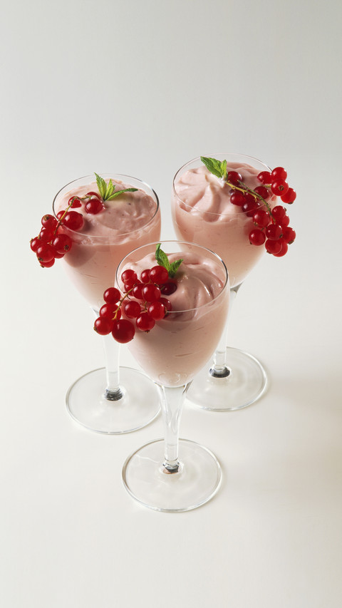 Three redcurrant cream desserts served in stemmed glasses preview