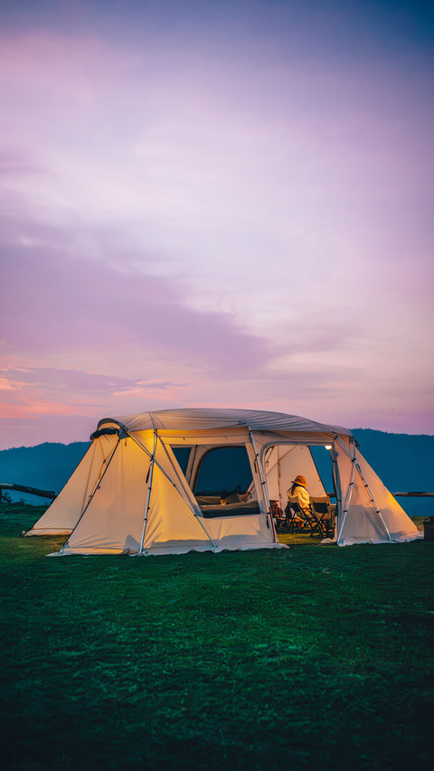 A woman sitting in a white tent during twilight time preview