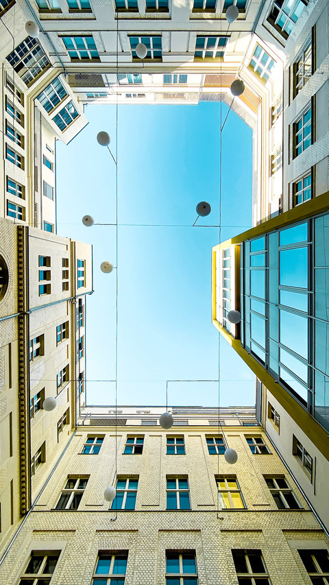 Low angle view courtyard of apartment block against blue sky preview