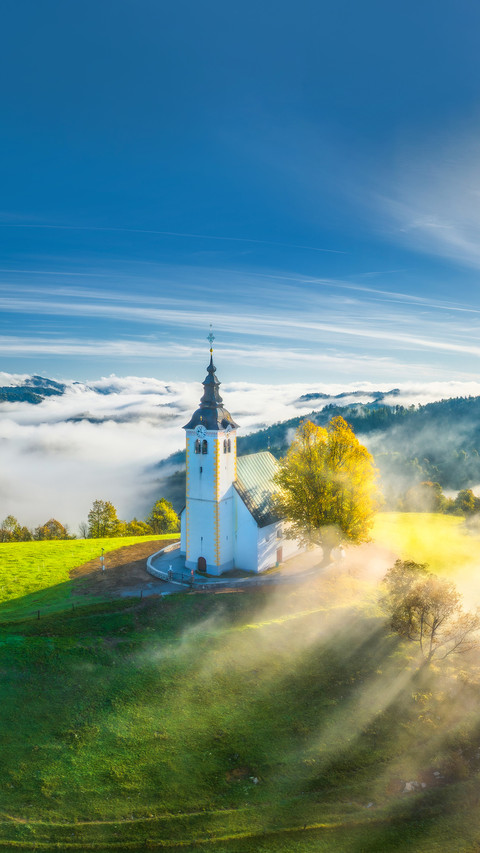 View of small church on the hill in low clouds at sunrise preview