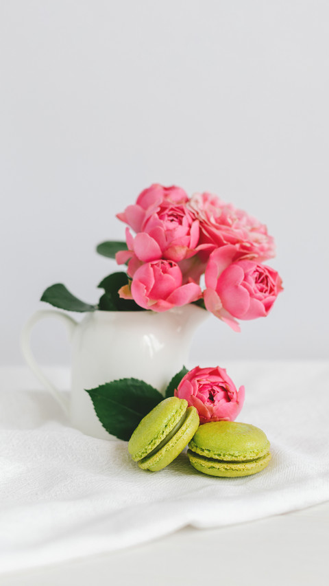Two tasty French macarons and a jar with beautiful roses preview