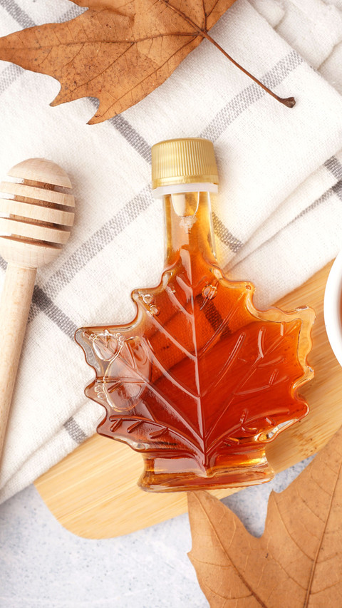 Bottle of tasty maple syrup on table preview