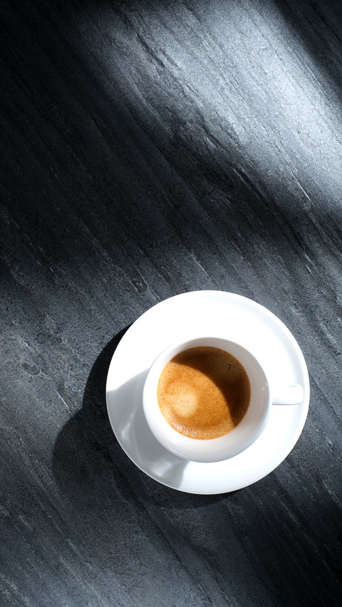 White cup with coffee on a black textured stone table preview