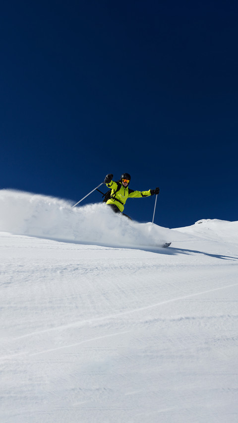 Alpine skier skiing downhill, blue sky on background preview
