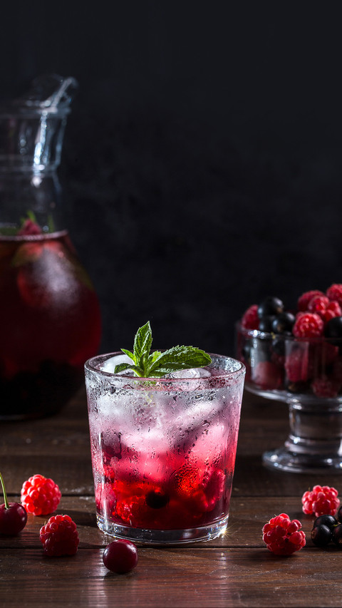 Berry lemonade in a transparent glass on a dark background preview