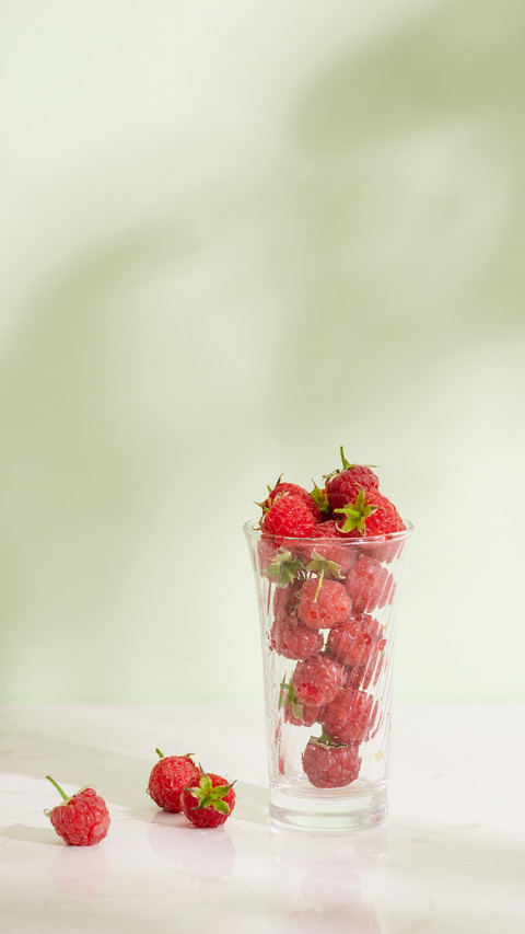 Fresh raspberries in a glass beaker on light background preview