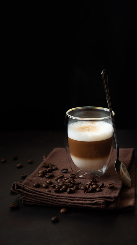 The thermo glass cup of latte coffee on dark wooden table preview