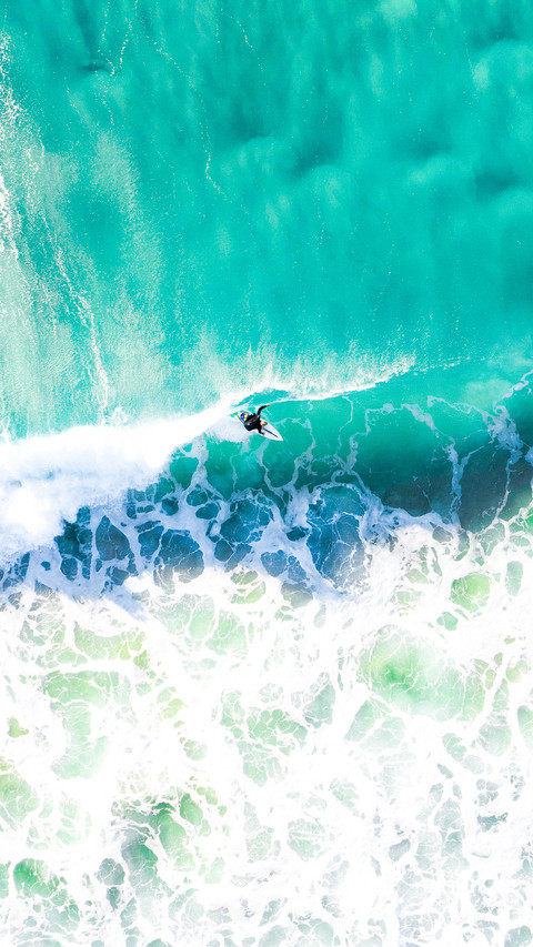Surfer surfing a wave at sunrise in a blue turquoise ocean preview