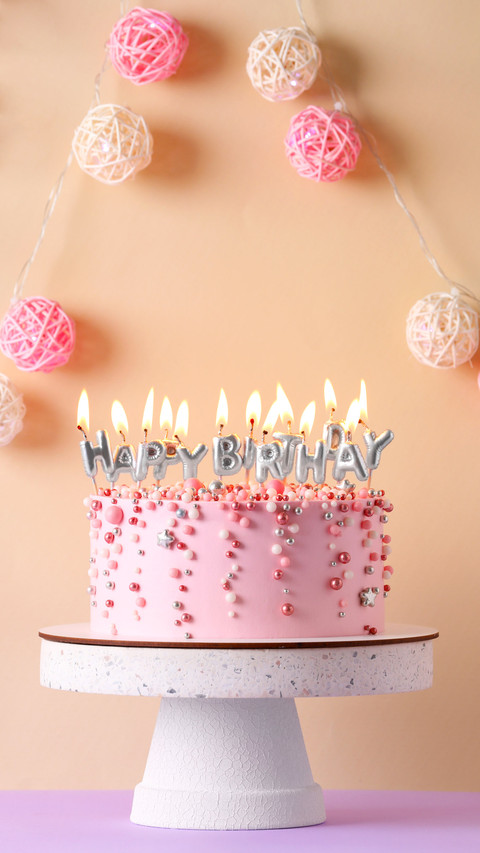 Birthday cake with burning candles on violet table preview