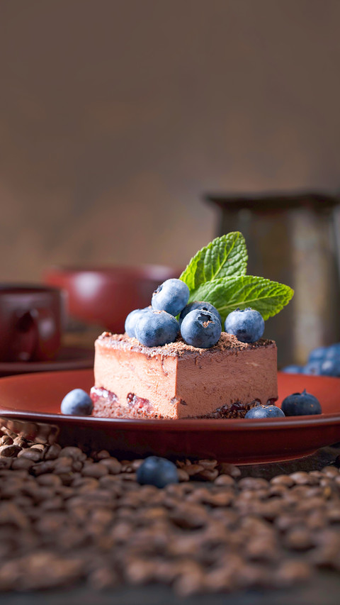 Chocolate cake with blueberries and mint on a brown plate preview