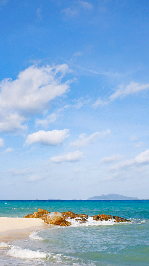 Clean beach and stones extending into body of blue sea preview
