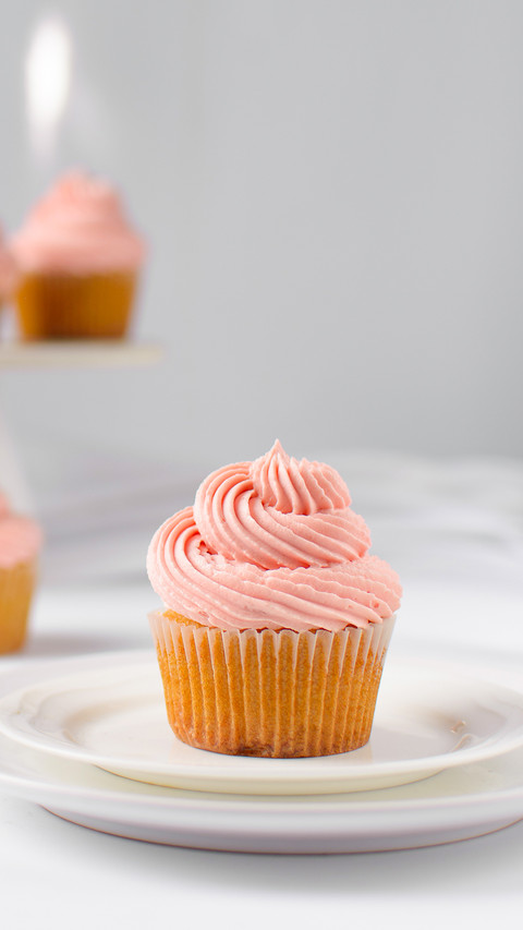 Vanilla cupcake with pink buttercream on a plate preview