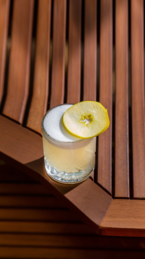 Cocktail with ice, apple and froth in a glass on the table preview